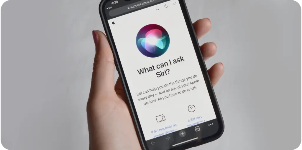 Image of a hand holding a phone with the message, "What can I ask Siri?"